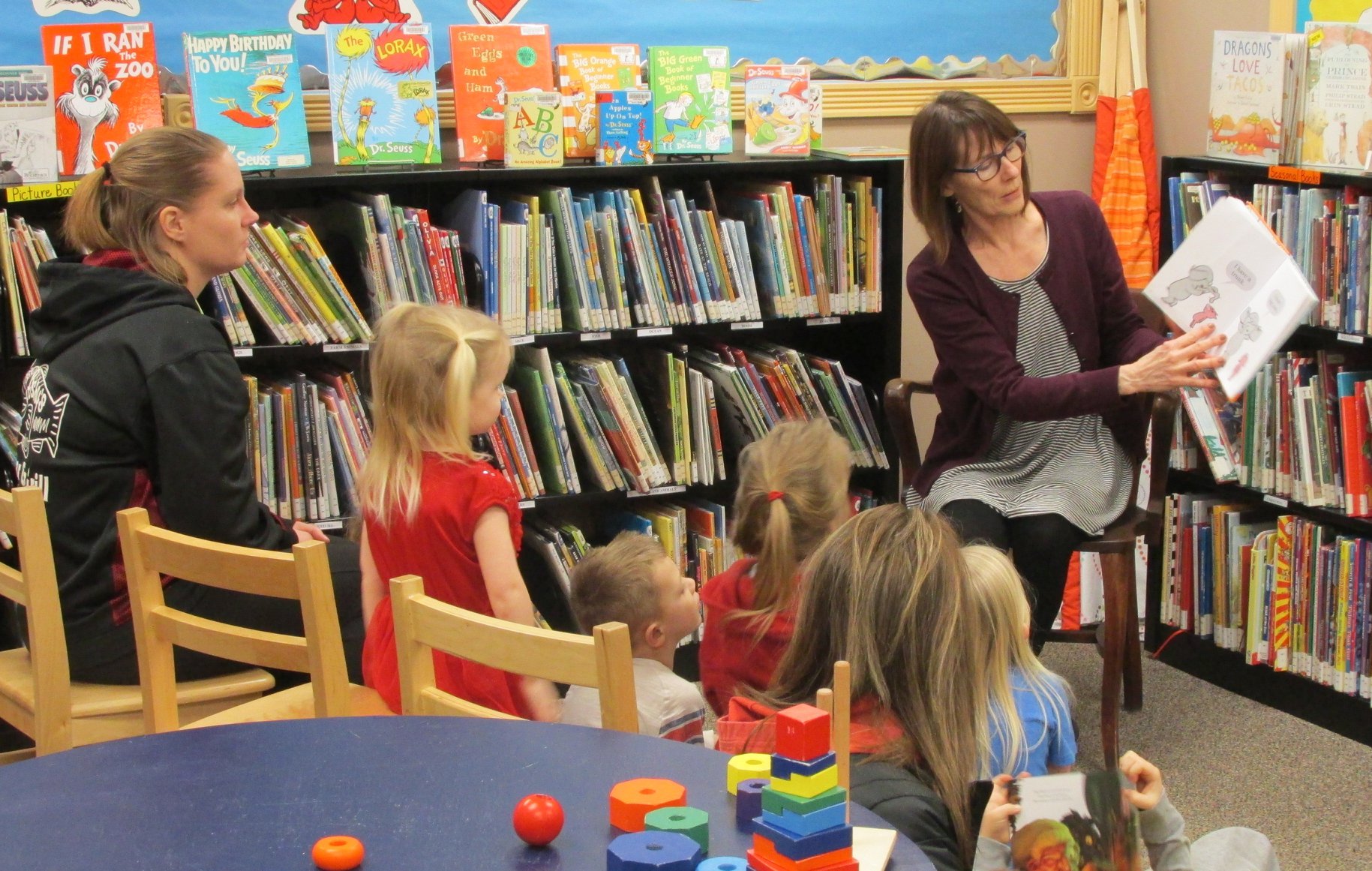 Librarian reads a story to a group of kids and their parents