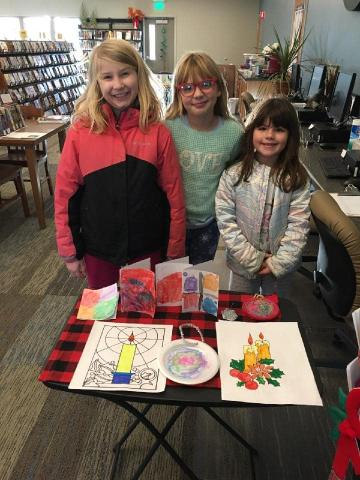 Three girls with holiday cards, pictures, and ornaments